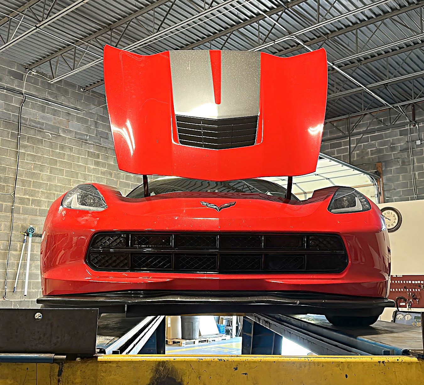 Red Corvette up on a lift inside the Unique Auto Mobile Care shop