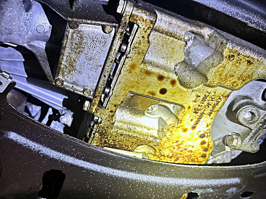 Technician inspecting the underside of a vehicle with a flashlight